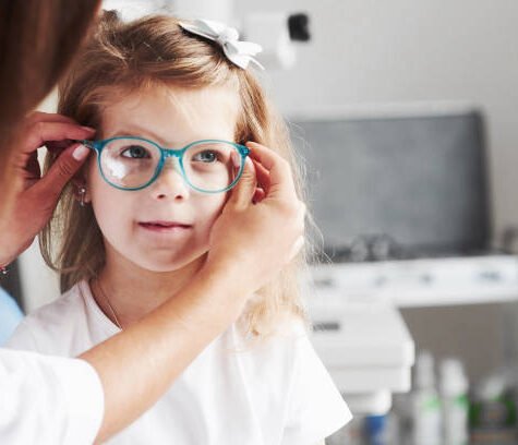 New look. Doctor giving the child new glasses for her vision.