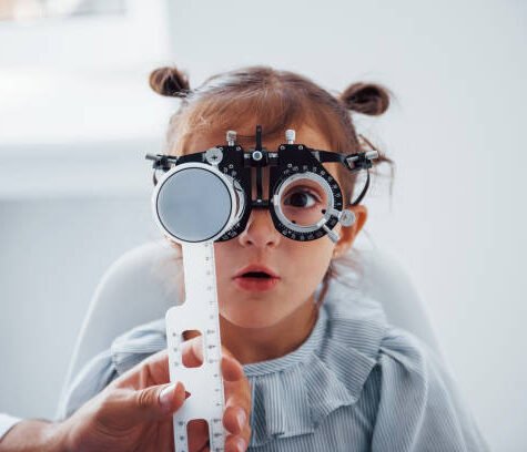 Little girl in eyewear in ophthalmology clinic have test of vision.