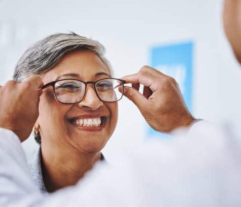 Optometry, smile and woman with prescription glasses, optician and helping client with product. Female person, employee and optometrist assist with eyewear, clear vision and buying new spectacles